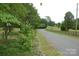 Scenic driveway lined with mature trees and black wooden fence leading to the property at 116 Lanes End Rd, Locust, NC 28097