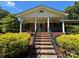 Charming brick home with a covered front porch, black railings, and landscaped garden beds at 116 Lanes End Rd, Locust, NC 28097