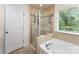 Full bathroom featuring tiled shower with glass door and soaking tub near a large window at 12408 Savannah Cottage Dr, Charlotte, NC 28273