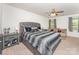 Main bedroom with a stylish upholstered headboard, neutral walls, and an inviting seating area at 12408 Savannah Cottage Dr, Charlotte, NC 28273