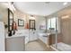 Bright bathroom featuring double sinks, a soaking tub, a glass-enclosed shower, and neutral toned tile flooring at 132 Flora Vista Dr, Mooresville, NC 28117