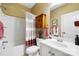 Well-lit bathroom features a shower-tub combo, updated vanity, wood storage cabinet, and red striped shower curtain at 132 Flora Vista Dr, Mooresville, NC 28117