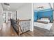 Hallway with wood floors, iron railing, and a view into a bedroom with blue accent wall and king-size bed at 1437 Imperial Ct, York, SC 29745