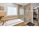 Bathroom featuring shower, soaking tub, decorative tile, and glass block window at 14505 Sunset Walk Ln, Huntersville, NC 28078