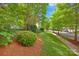 Landscaped front yard with lush greenery and mature trees lining the street, creating curb appeal at 14505 Sunset Walk Ln, Huntersville, NC 28078