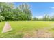 Large backyard with a grassy lawn, edged by mature trees and a sidewalk at 151 Deja Ln, Cleveland, NC 27013