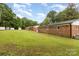 Back view of the brick home with green grass, storage units, and trees at 16 Green St, York, SC 29745