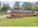 Backyard view of brick home with carport, mature trees, and spacious lawn at 16 Green St, York, SC 29745