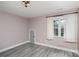 Neutral-toned bedroom featuring hardwood floors, a window with curtains, and natural light at 17318 Cambridge Grove Dr, Huntersville, NC 28078