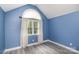 Bright bedroom with blue walls, hardwood floors, and a large window with white curtains at 17318 Cambridge Grove Dr, Huntersville, NC 28078