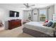 Bright main bedroom with a ceiling fan, dresser, television, and views from two large windows at 2178 Stone Pile Sw Dr, Concord, NC 28025