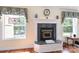 Close-up of a fireplace with a marble surround, windows, wooden floors, and decor at 408 Emerald Bay Dr, Salisbury, NC 28146