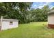 View of the expansive backyard featuring a storage shed, green grass, and mature trees, offering a private outdoor space at 4915 Galax Dr, Charlotte, NC 28213