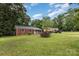 Brick ranch home situated on a large lot with a long gravel driveway and mature trees at 4915 Galax Dr, Charlotte, NC 28213