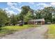 A well-maintained brick ranch home featuring a gravel driveway and mature shade trees at 4915 Galax Dr, Charlotte, NC 28213