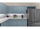 This kitchen features blue cabinets, stainless steel appliances, light countertops with wine rack above the refrigerator at 507 Galesburg Dr, Monroe, NC 28110