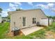 Cozy back patio with a white door, window, and partial white fence surrounded by green grass and blue skies at 5402 Harris Cove Dr, Charlotte, NC 28269
