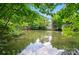Scenic water view featuring a serene pond surrounded by lush greenery and a quaint building nestled in the trees at 8014 Sherington Way, Charlotte, NC 28227