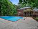 Expansive backyard with mature trees and a large in-ground pool next to an ample brick home at 8527 Foxbridge Dr, Matthews, NC 28104