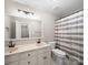 Bright bathroom featuring double vanity, black hardware, toilet, and shower with white and grey curtain at 8527 Foxbridge Dr, Matthews, NC 28104