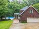 Exterior view of a brick home with a pool, screened porch, and a two-car garage at 8527 Foxbridge Dr, Matthews, NC 28104