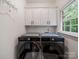 Modern laundry room with side-by-side machines and white cabinets at 8527 Foxbridge Dr, Matthews, NC 28104