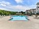 A community pool overlooks a lake with apartment buildings and outdoor tables and chairs for residents at 930 Jetton St, Davidson, NC 28036
