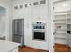 Bright white kitchen features stainless steel appliances, white cabinetry and hardwood floors at 9311 Simpson Rd, Waxhaw, NC 28173