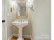 Stylish powder room features a pedestal sink, decorative mirror, and elegant wall sconces at 9315 Simpson Rd, Waxhaw, NC 28173