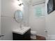 Neat half bathroom featuring a vanity with sink, round mirror, and natural light from the window at 11945 Red Rust Ln, Charlotte, NC 28277