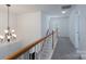 Upstairs hallway featuring chandelier and wood railing at 11945 Red Rust Ln, Charlotte, NC 28277