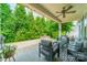 Cozy covered patio with a seating area, ceiling fan, string lights, and views of the lush backyard at 12107 Grey Partridge Dr, Charlotte, NC 28278