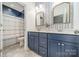 Stylish bathroom featuring double sinks, blue vanity, patterned wallpaper, and a shower with curtain at 12107 Grey Partridge Dr, Charlotte, NC 28278