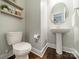 Cozy powder room with wood floors, pedestal sink, toilet, and modern floating wood shelves at 12107 Grey Partridge Dr, Charlotte, NC 28278