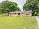 Well-kept brick home features a large front lawn, mature trees, and a welcoming entrance at 1325 Marshville Olive Branch Rd, Marshville, NC 28103