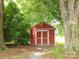 Exterior view of a red storage shed nestled among trees in a lush, green yard at 1325 Marshville Olive Branch Rd, Marshville, NC 28103
