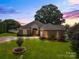Charming brick home with a lush lawn, manicured landscaping, and a well-lit driveway at twilight at 133 43Rd Avenue Nw Ln, Hickory, NC 28601