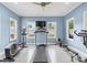 Home gym featuring light blue walls, a ceiling fan, and windows overlooking a fenced-in yard at 133 43Rd Avenue Nw Ln, Hickory, NC 28601