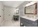 Bright bathroom featuring gray double vanities, marble countertops, framed mirrors, and wood-look tile floors at 1522 Barberry Ct, Charlotte, NC 28211