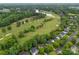 Aerial view showcasing a golf course community with lush green fairways, a lake, and beautiful homes at 15301 Marsh Field Ct, Huntersville, NC 28078