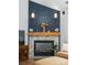 Cozy fireplace with a stone surround, wooden mantle, blue wall paneling, and stylish decor at 15301 Marsh Field Ct, Huntersville, NC 28078