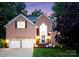 Charming brick home with a welcoming blue front door, manicured lawn, and two-car garage at twilight at 15301 Marsh Field Ct, Huntersville, NC 28078