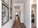 Inviting hallway featuring wood flooring, elegant artwork, crown molding, and views into the living spaces and bedroom at 1600 Baymont Ct, Stanley, NC 28164