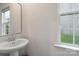 Small powder room features pedestal sink, mirror, and bright window at 17812 New Mark Ave, Charlotte, NC 28278