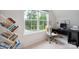 Bright home office with modern desk, white and gold chair, and open shelving to display books next to a large, sunny window at 17812 New Mark Ave, Charlotte, NC 28278