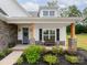 Cozy front porch with stone accents, natural wood posts, bench, and beautifully landscaped garden beds at 182 Mackenzie Ct, China Grove, NC 28023
