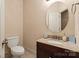 Well-lit bathroom with granite countertop, round mirror, and beige textured walls at 1974 Glen Manor Ct, Lincolnton, NC 28092