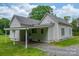 Charming home with a covered carport and gravel driveway, set against a backdrop of lush greenery and a partly cloudy sky at 2126 Robby Dr, Maiden, NC 28650