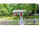 Charming brick home with a bright red door, white picket fence and lush green lawn and mature trees at 220 Pinehurst Ln, Newton, NC 28658