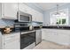Well-lit kitchen featuring stainless steel appliances, black countertops, and white cabinets with tile floors at 220 Pinehurst Ln, Newton, NC 28658